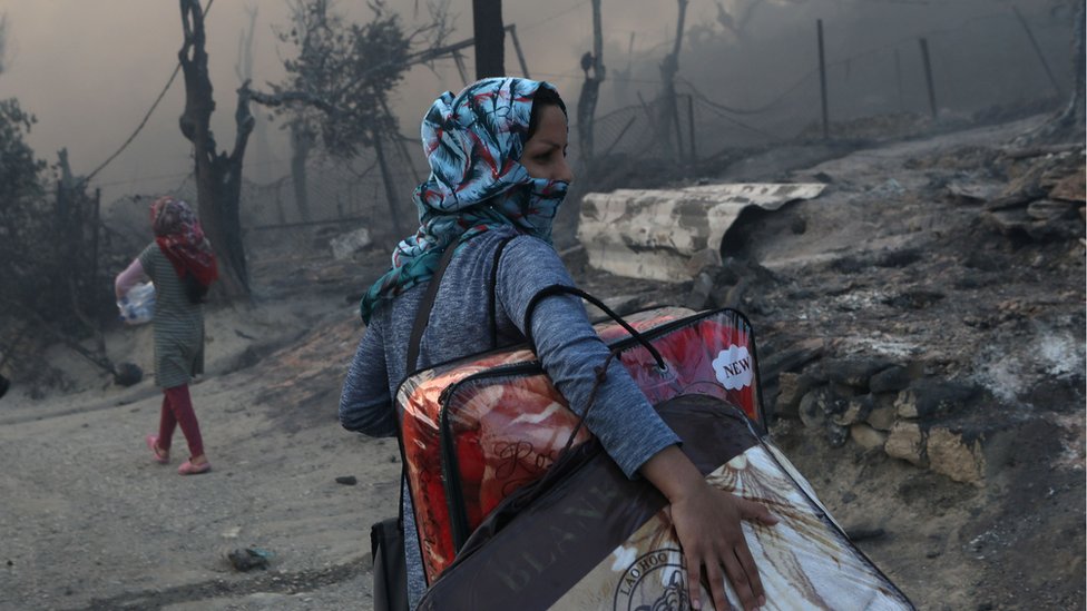 Migrants leave the remains of Moria refugee camp