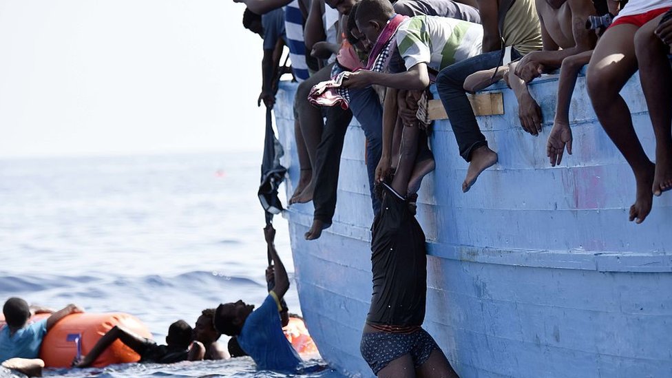 Мигрант висит на лодке, ожидая спасения, дрейфуя в Средиземном море, примерно в 12 морских милях к северу от Ливии, 4 октября 2016 года.