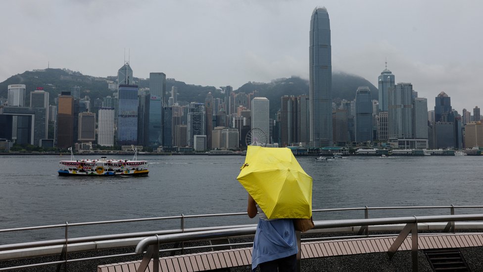 香港九龍尖沙咀海旁一位女士打起黃色雨傘眺望維多利亞港（11/8/2023）