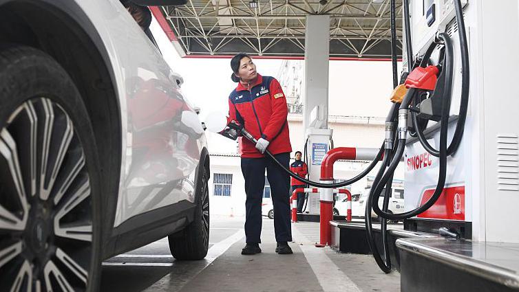 A driver refuels a white car as China scales back planned fuel price hikes.