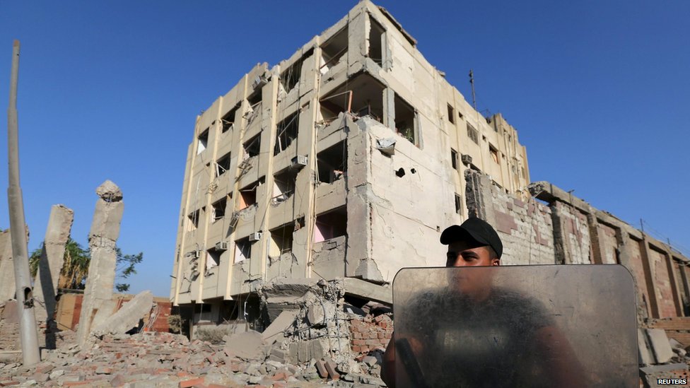 Сотрудник службы безопасности охраняет место взрыва бомбы в здании государственной безопасности в Шубра-Аль-Хайма, на окраине Каира (20 августа 2015 г.)