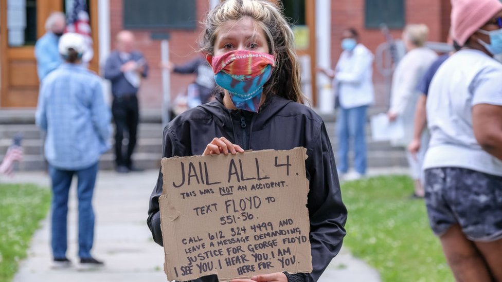 Mujer con un cartel que dice "encarcelen a los 4"