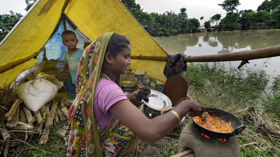 Женщина готовит еду, пока ее мальчик наблюдает за спасательным лагерем в пострадавшем от наводнения районе Моригаон штата Ассам, Индия, 2 сентября 2015 г.