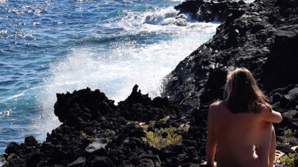 A naturista britânica Donna Price sentada à beira-mar