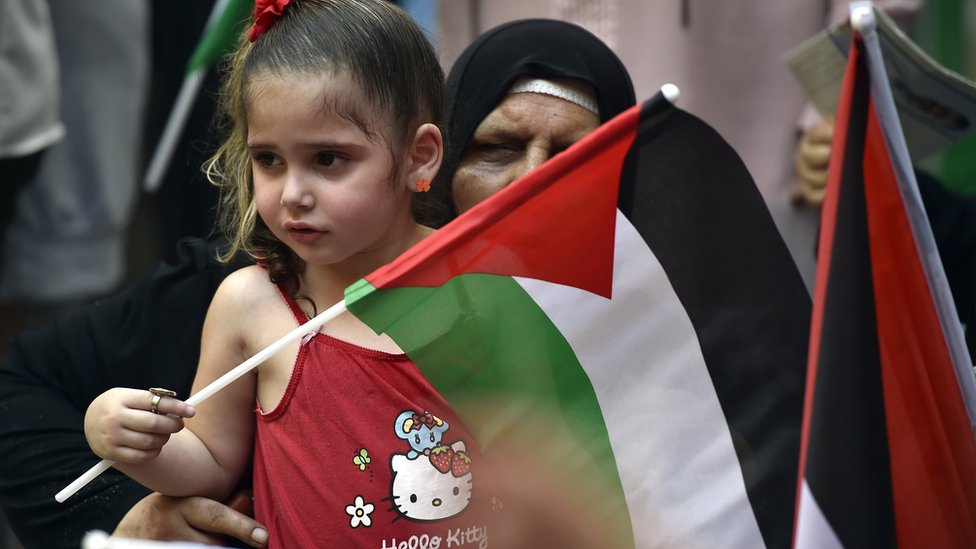 A girl carrying the Palestinian flag