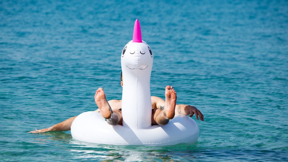Hombre flotando en un inflable de unicornio