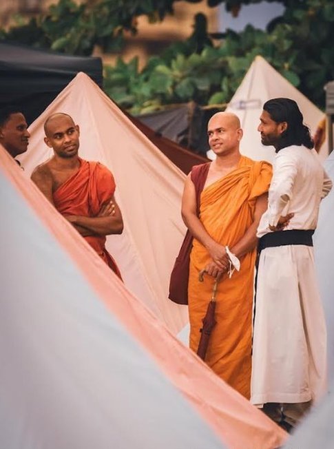 Buddhist monks stand between tents with protesters
