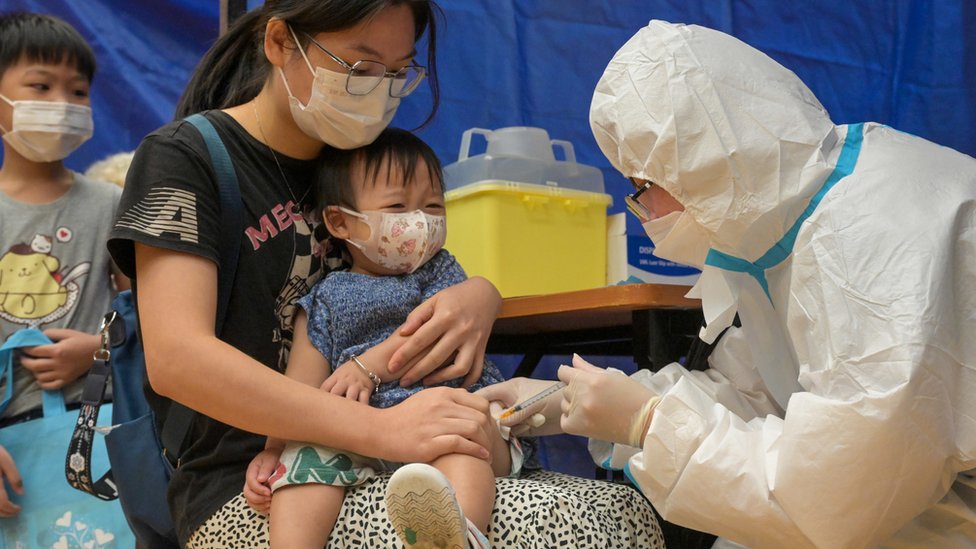 香港某疫苗接種中心一名身穿全套個人防護裝備的醫療人員為一名幼童接種疫苗（中新社圖片28/8/2022）