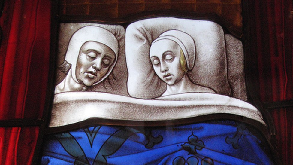 Vidriera medieval de una iglesia que muestra a una pareja del Medievo durmiendo