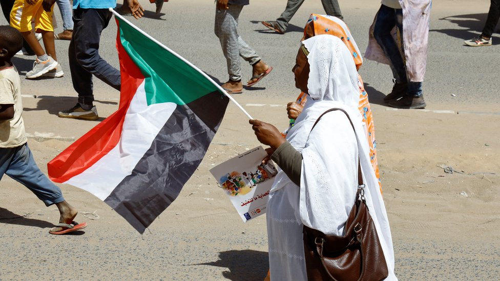امرأة سودانية تحمل العلم خلال مظاهرة ضد الانقلاب العسكري، في يوم المرأة العالمي في الخرطوم، السودان، 8 مارس/آذار