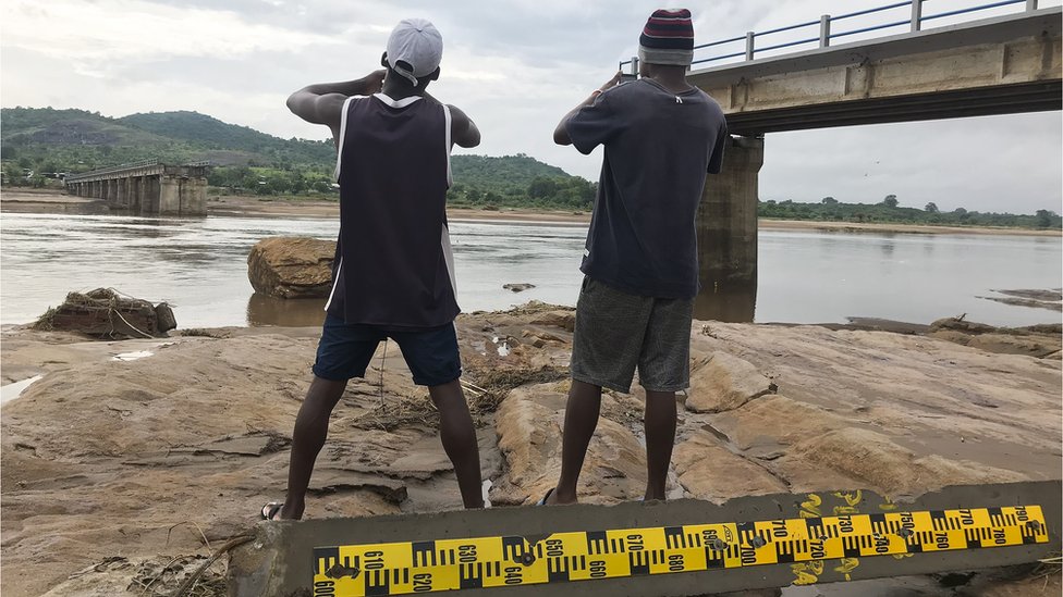رجلان يلتقطان صورا لجسر مدمر في موزمبيق