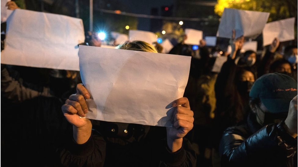 Manifestantes en China sostienen hojas blancas en forma de protesta.