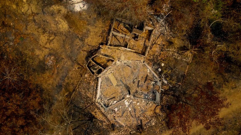 An aerial view of a burnt out building in the middle of a burnt forest