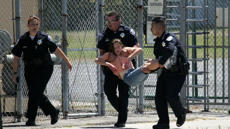 Una estudiante voluntaria es cargada por policías en un simulacro.