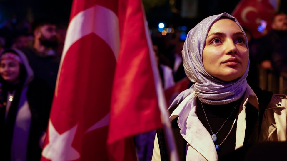 فتاة محجبة تقف بجوار علم تركيا