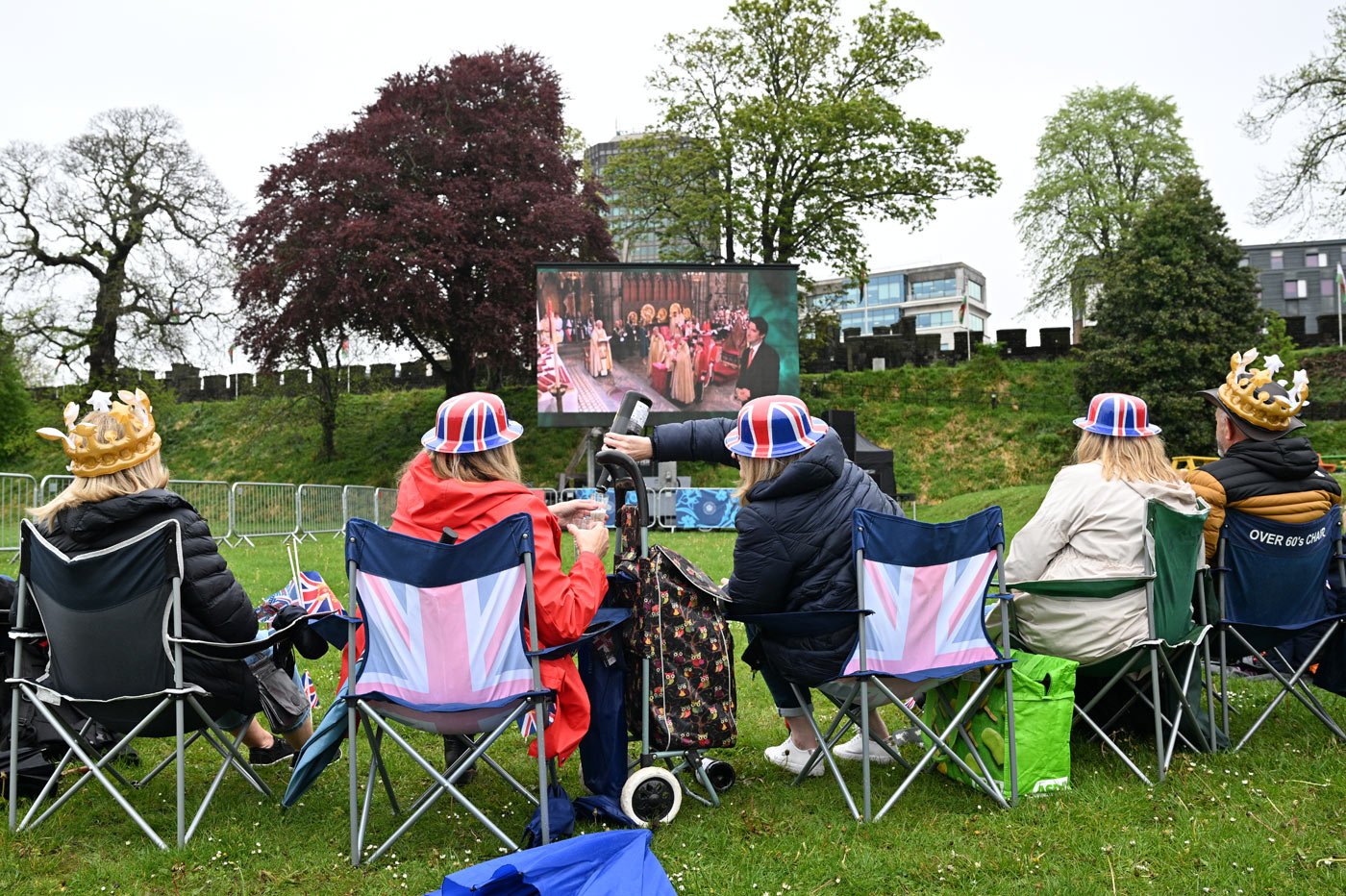 People watch the coronation ceremony on a big screen in the grounds of Cardiff Castle