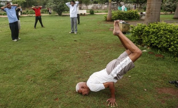 Индийские мужчины практикуют йогу в парке Jogger's в Мумбаи, Индия, 16 июня 2015 г.