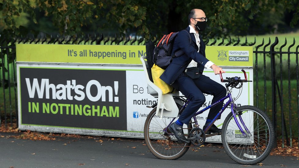 Мужчина на велосипеде проезжает мимо знака «Что происходит в Ноттингеме»