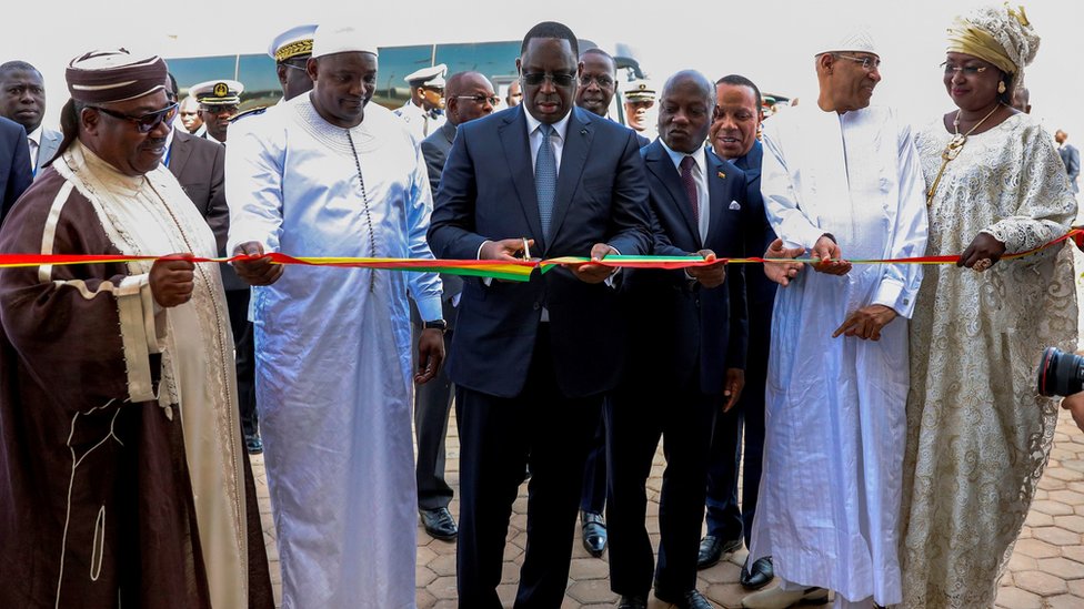 Президент Сенегала Маки Салл (в центре) наблюдает за его женой Марием Фэй Салл (справа) и региональными лидерами, когда он перерезает церемониальную ленту на церемонии открытия нового международного аэропорта имени Блеза Диань - 7 декабря