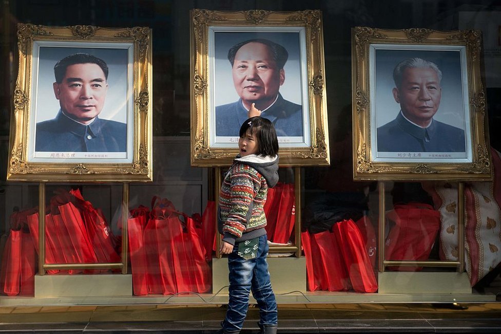 2013年2月26日，一個女孩站在中國前領導人（從左到右）周恩來、毛澤東和劉少奇的畫像前。