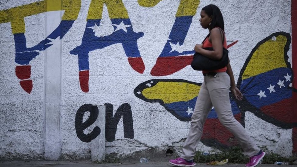 Женщина проходит мимо фрески, призывающей к миру в Венесуэле во время выборов в Учредительное собрание в Каракасе, Венесуэла, 30 июля 2017 года.