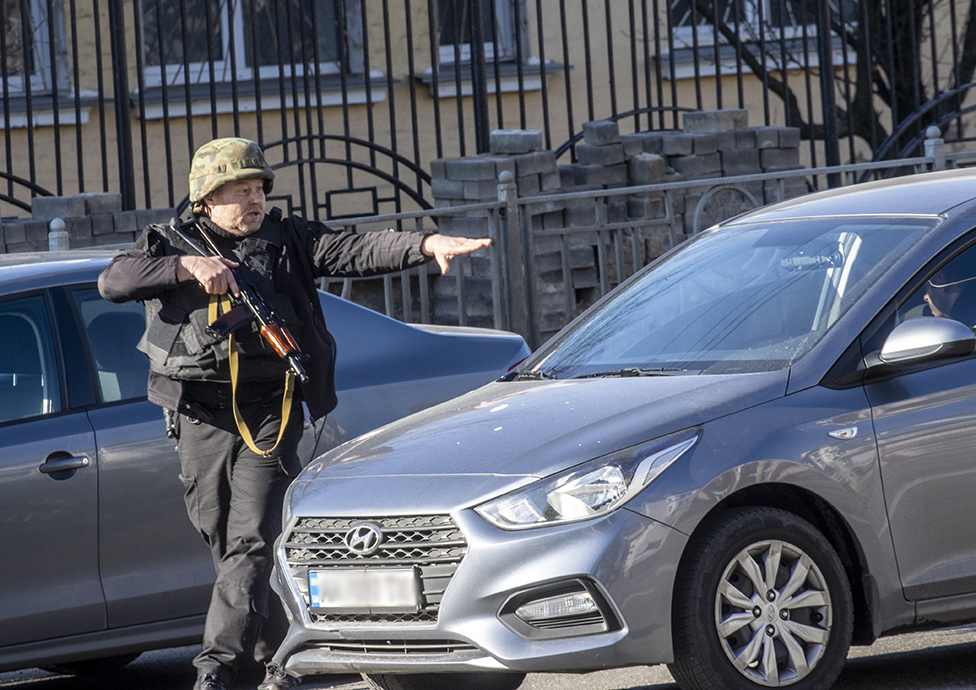 Un soldado ucraniano inspecciona vehículos en el barrio de Zhuliany en Kiev