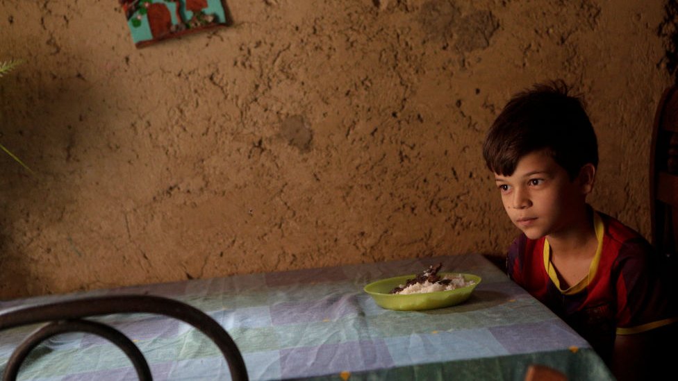 Niño venezolano frente a un plato de comida