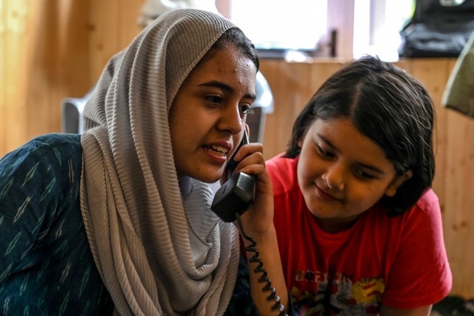 На этой фотографии, сделанной 17 августа 2019 года, кашмирские мусульмане разговаривают с родственниками по стационарному телефону в Шринагаре