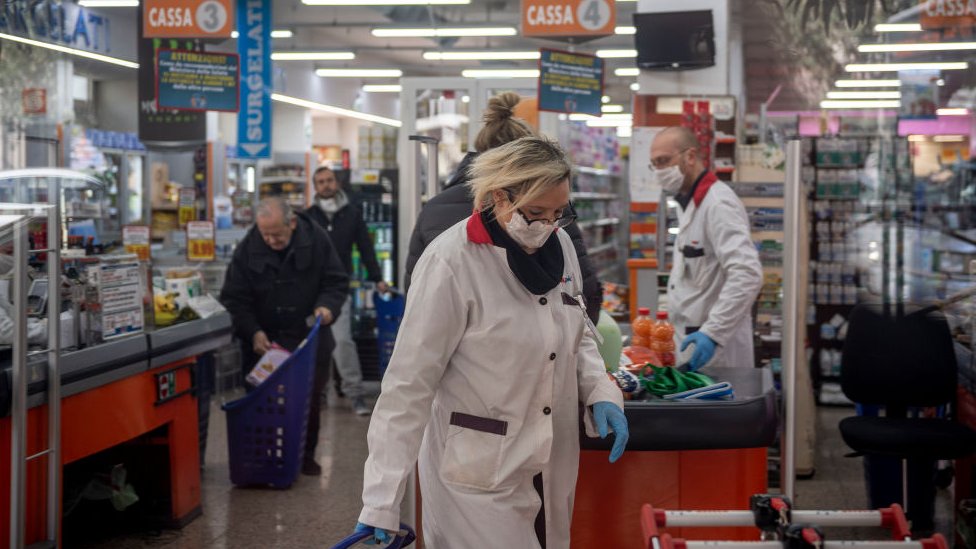 Italianos con mascarillas en un supermercado en Italia