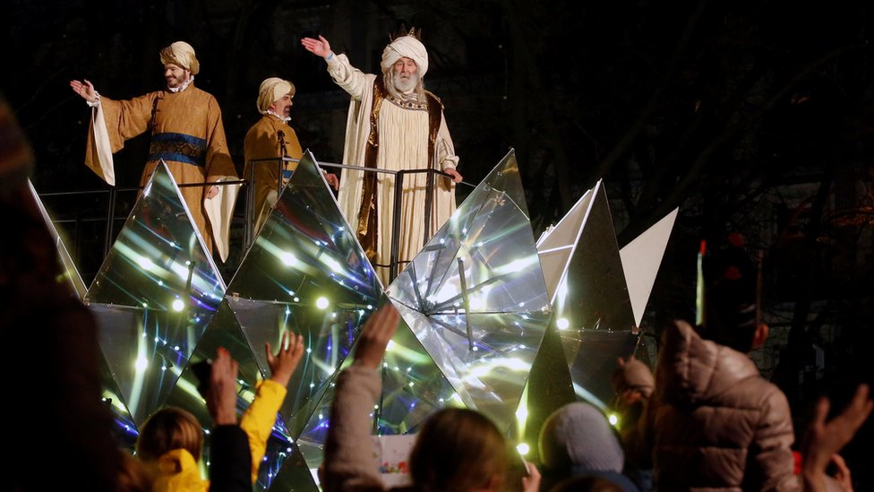 Мужчины, одетые как Три волхва, машут толпе, собравшейся в Мадриде в Испании, чтобы отпраздновать праздник Богоявления