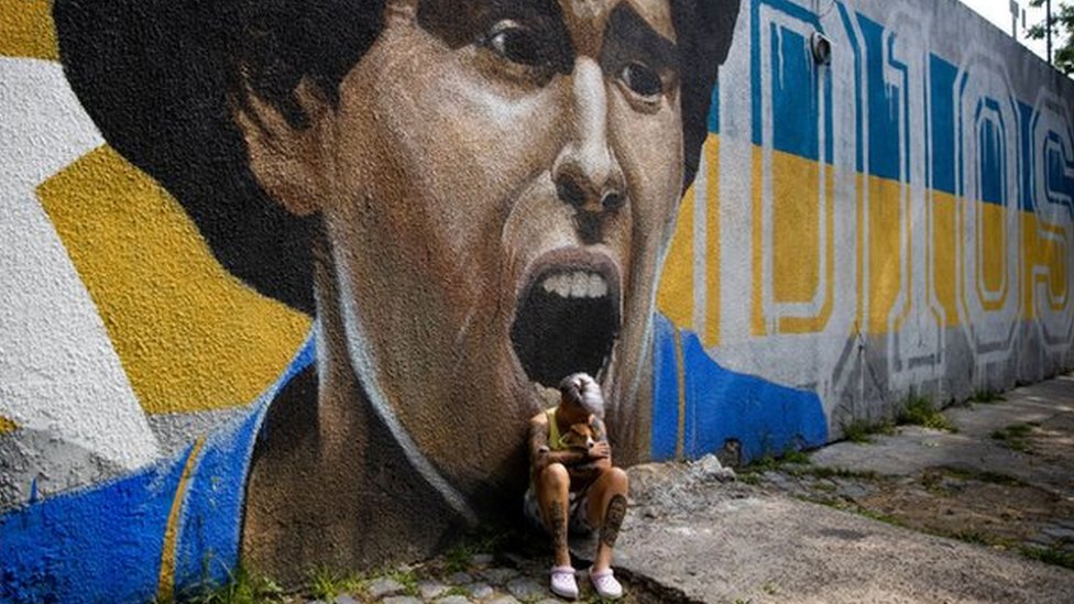 Boca Juniors women's player Yamila Rodriguez cries in front of graffiti image of Diego Maradona