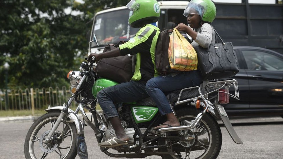 Нигерийский мотоциклист проезжает через пробку в Лагосе со своим пассажиром