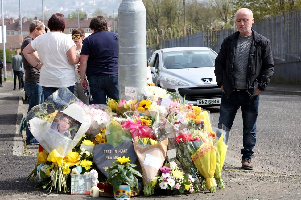 Мужчина смотрит на цветочные дань уважения Лайре МакКи недалеко от места, где она была снята в Лондондерри