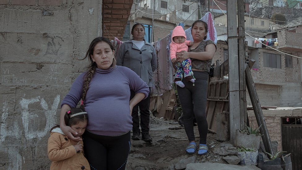 Синтия Эстрада Боливар (31 год) и ее трехлетняя дочь стоят перед своим домом в сопровождении родственников.