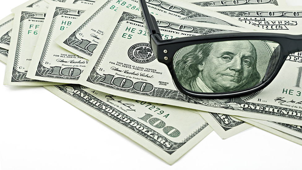 Unos anteojos que agrandan la imagen del rostro de Benjamin Franklin en el billete de US$100.