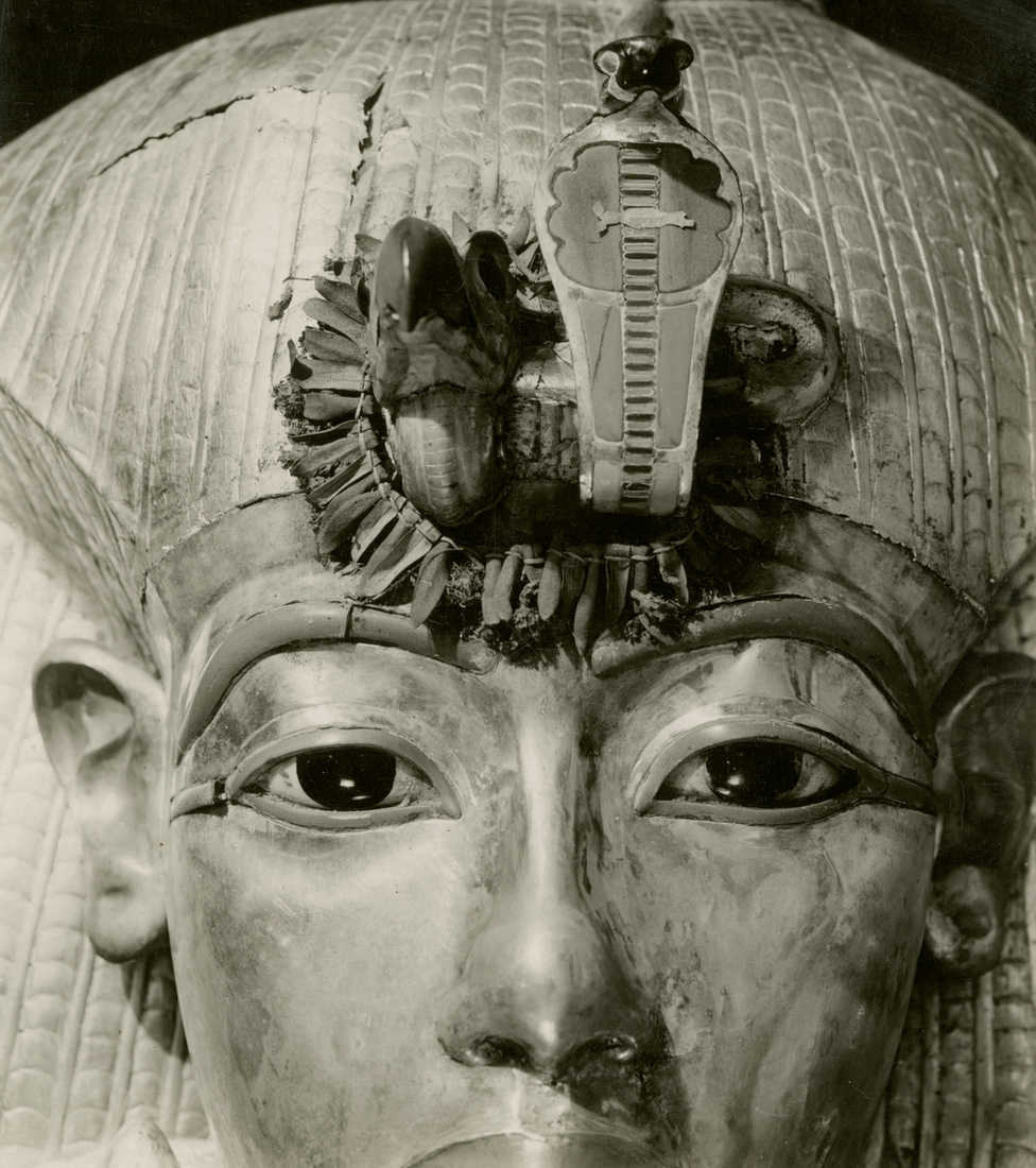 Close da máscara de Tutancâmon e de um adorno de flores e folhas ao redor da serpente na testa