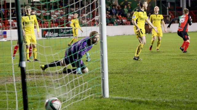Glentoran's Jonathan Smith scores past Cliftonville goalkeeper Conor Devlin at the Oval