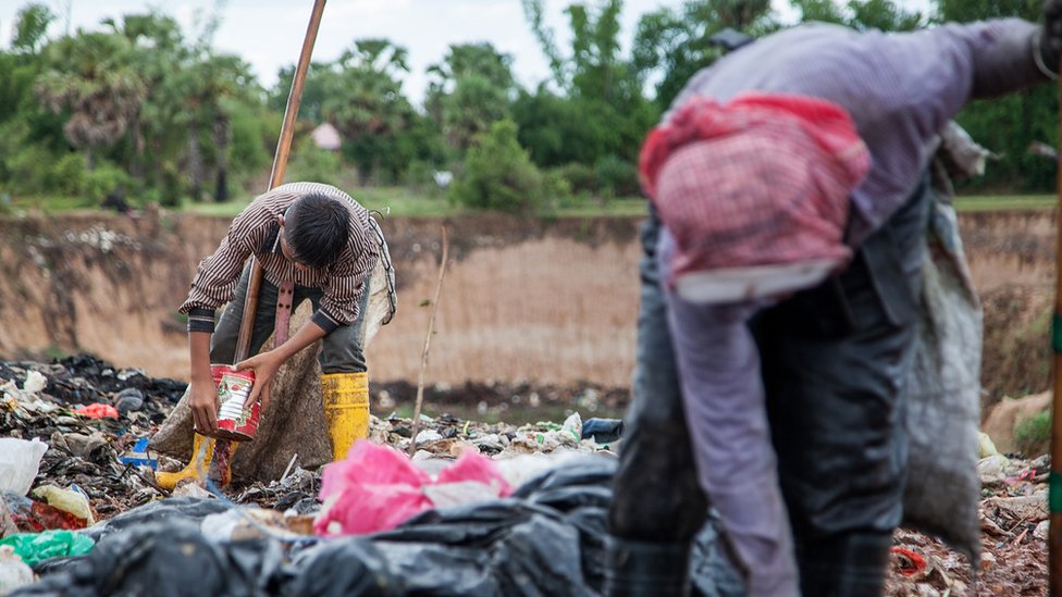 Jovens catadores trabalham em um aterro sanitário no Camboja, 2014, em busca de qualquer coisa de valor