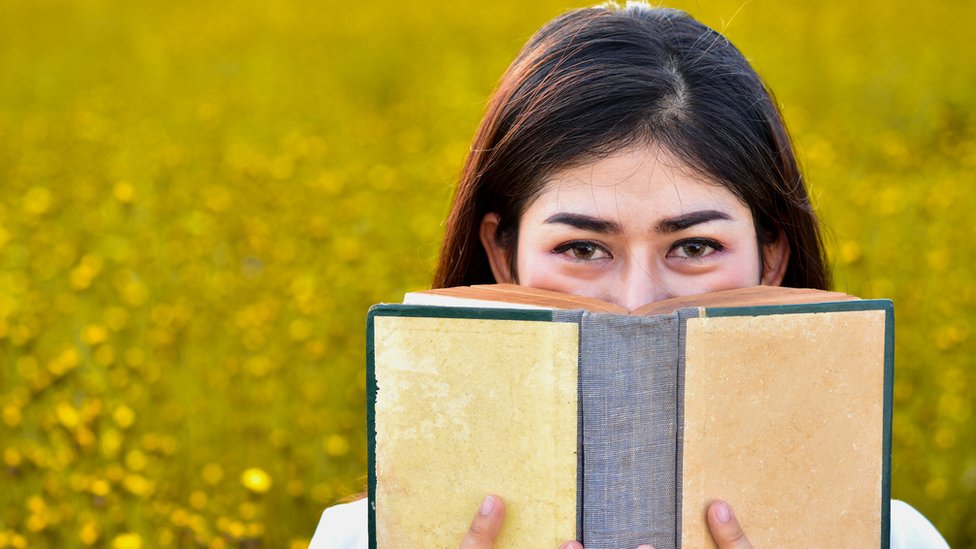 Una mujer joven huele un libro.