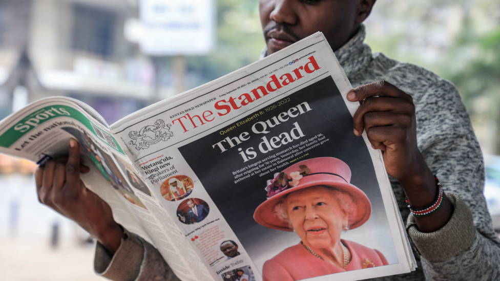 Un vendedor de periódicos leyendo un diario local que informa sobre la muerte de la reina Isabel II en la ciudad de Nairobi.