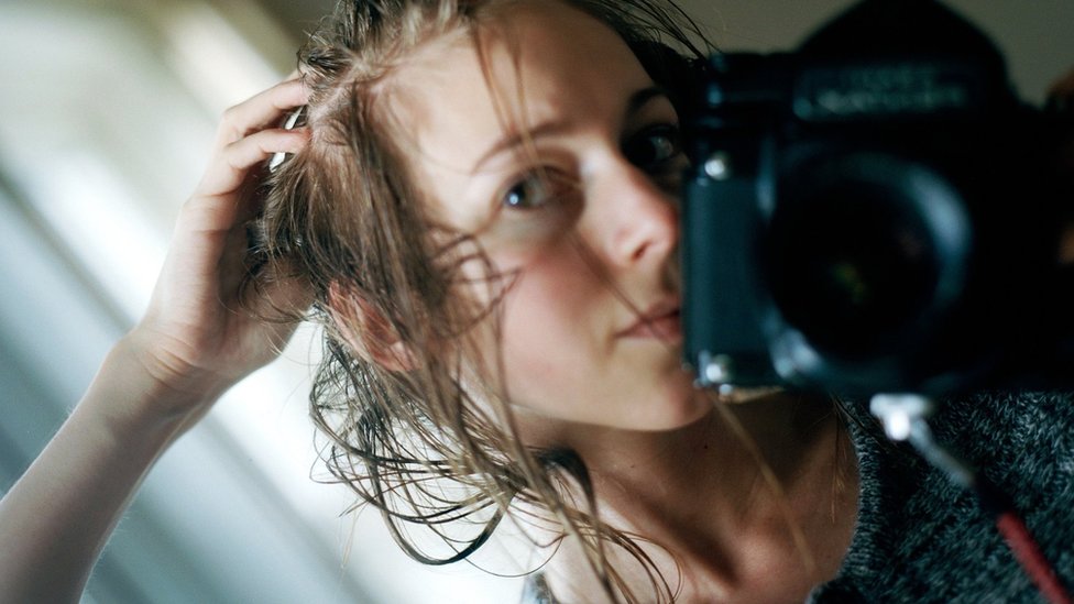 Carly Clarke photographs herself in the mirror at a time when her hair was falling out