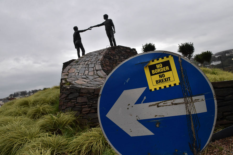 Наклейка «Нет границ - нет Брексита» рядом со статуей «Руки через разделительный мир»