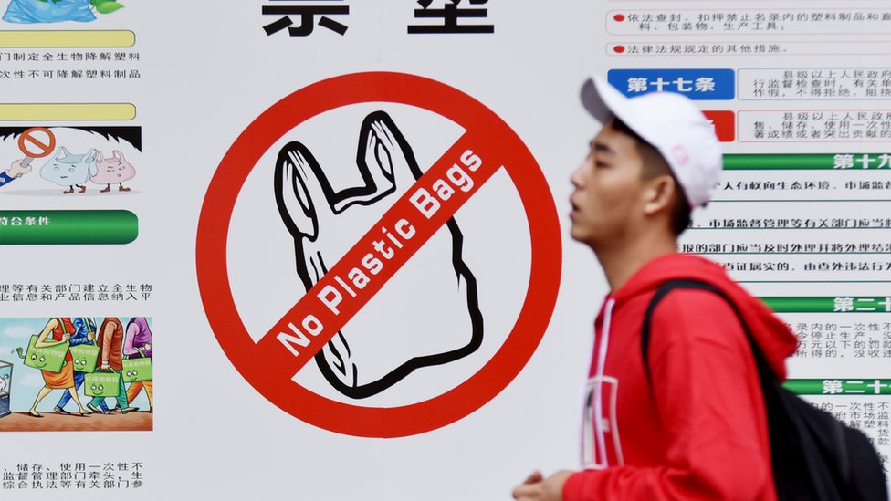 A university students passes a poster for banning plastic bags in Haikou, Hainan province, China, on November 30, 2020.