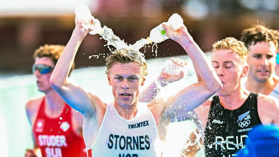 El triatleta Casper Stornes de Noruega se refresca con dos botellas de agua