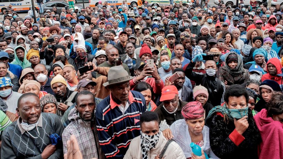 Неформальные продавцы собираются перед муниципальным офисным зданием в Браамфонтейне, Йоханнесбург, 8 апреля 2020 года, пытаясь получить разрешение на работу в течение 21-дневного национального карантина, который начался 27 марта 2020 года, в попытке остановить распространение вспышки коронавируса COVID-19