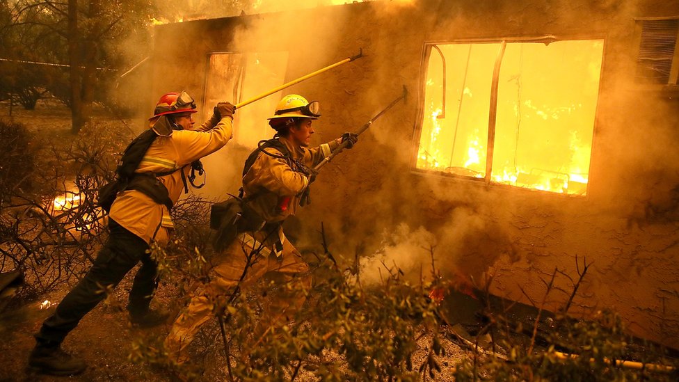 Пожарные пытаются предотвратить распространение пламени на соседний жилой комплекс во время борьбы с пожаром в лагере в ноябре 2018 года
