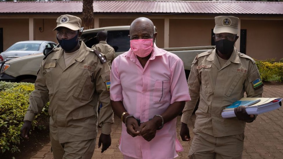 Герой «Hotel Rwanda» Пол Русесабагина (в центре) в розовой униформе заключенного прибывает в суд Ньяругенге в Кигали, Руанда, 2 октября 2020 года, в окружении охранников Исправительной службы Руанды (RCS).