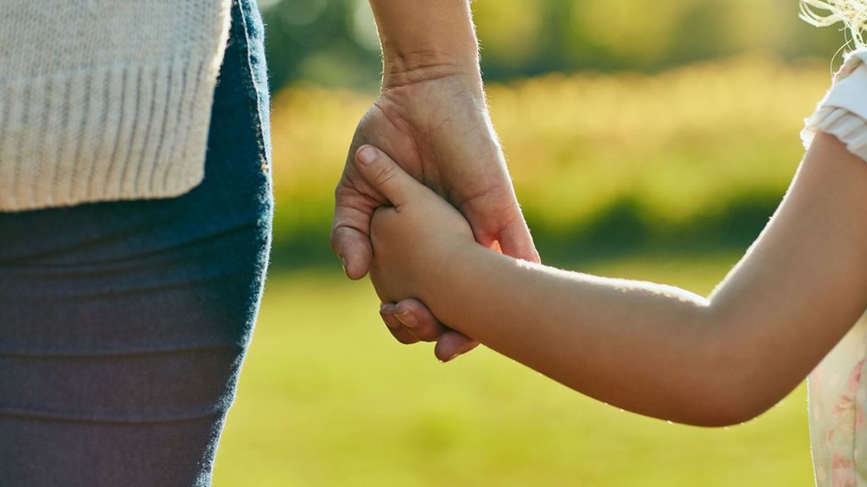 Ребенок и родитель держатся за руки