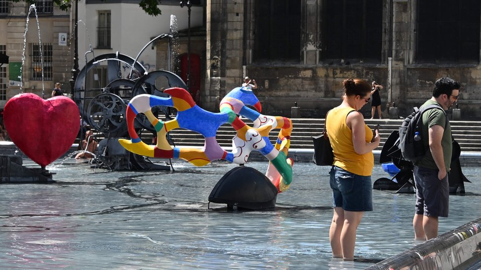 Два человека купают ноги в воде фонтана Стравинского в Париже