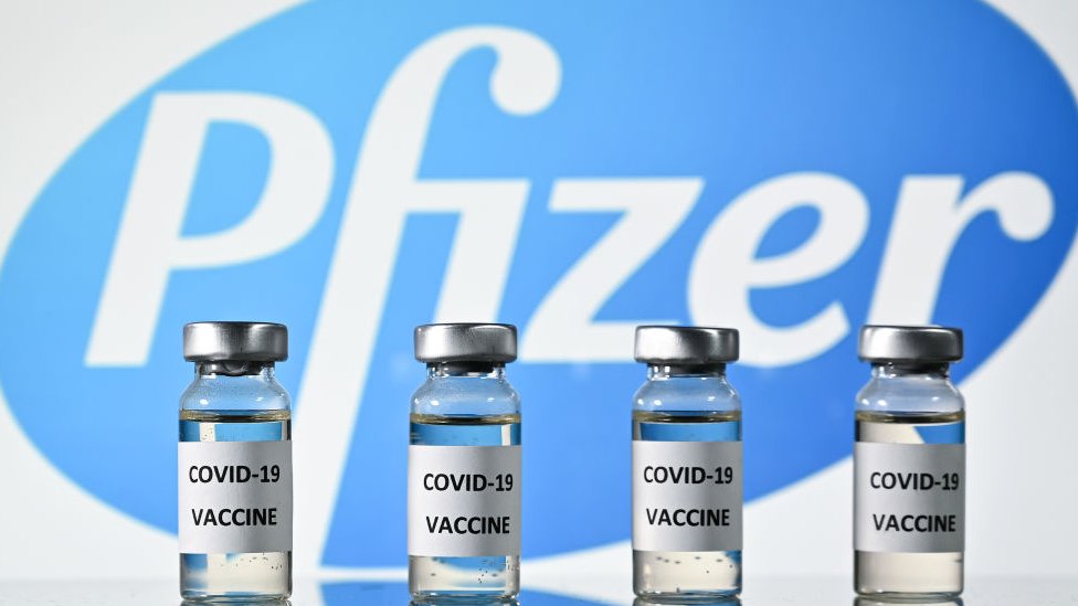 Logo de Pfizer con dosis de vacunas.